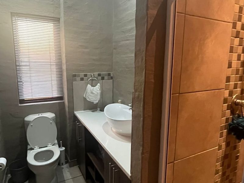 A functional bathroom featuring a vessel sink vanity, toilet, and a tiled shower enclosure with neutral finishes.