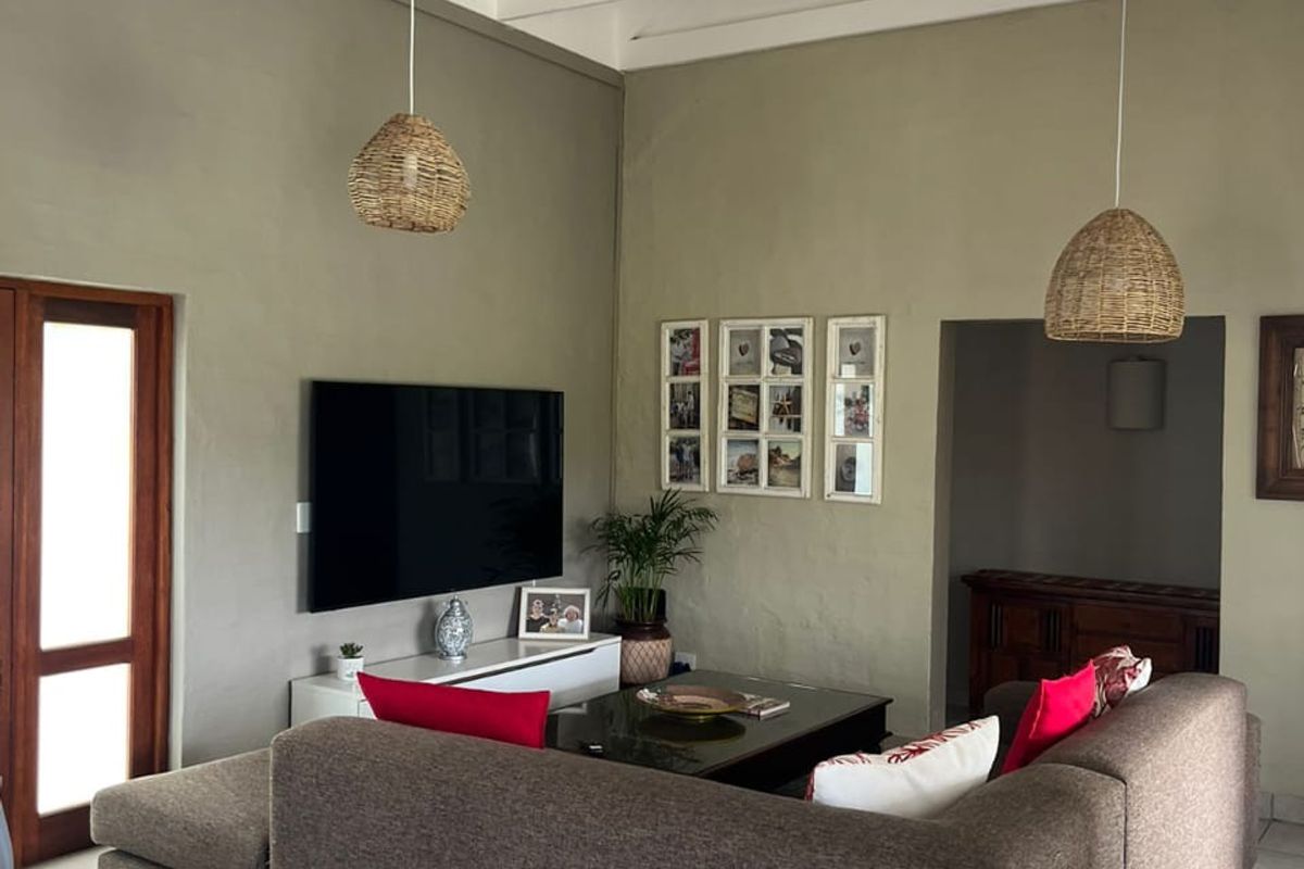 Spacious living room featuring high vaulted ceilings with exposed white timber trusses and neutral tiled flooring.