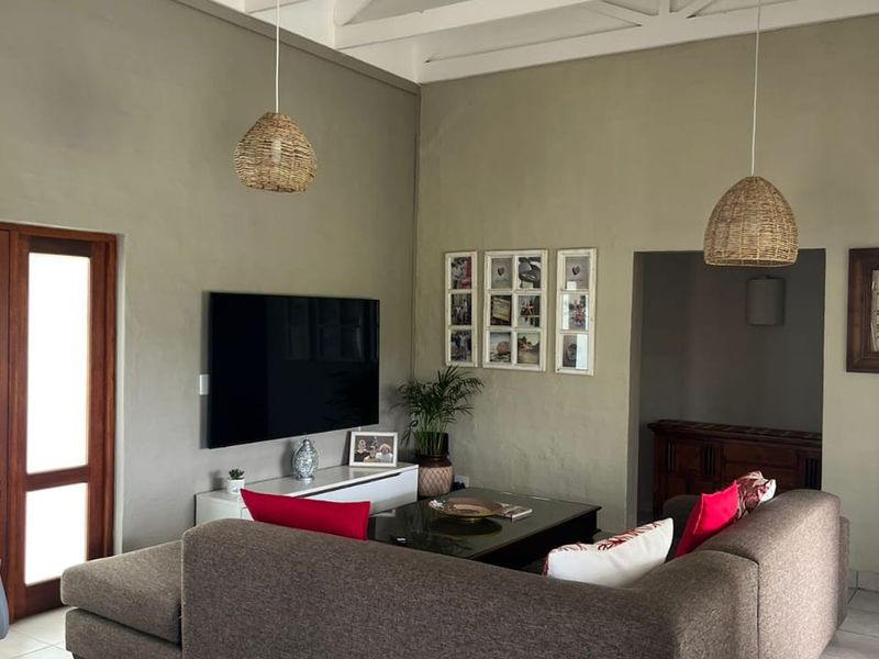 Spacious living room featuring high vaulted ceilings with exposed white timber trusses and neutral tiled flooring.