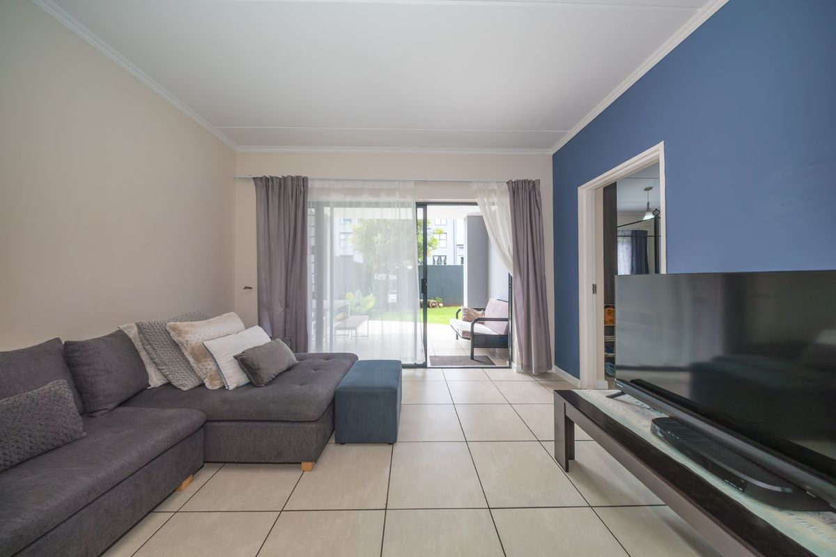 Bright living room featuring large sliding glass doors that provide direct access to the rear patio and garden area.