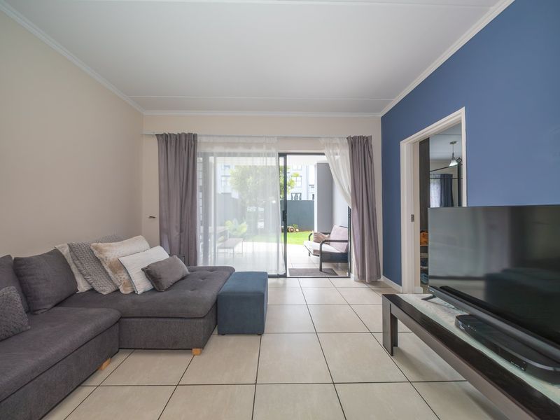 Bright living room featuring large sliding glass doors that provide direct access to the rear patio and garden area.