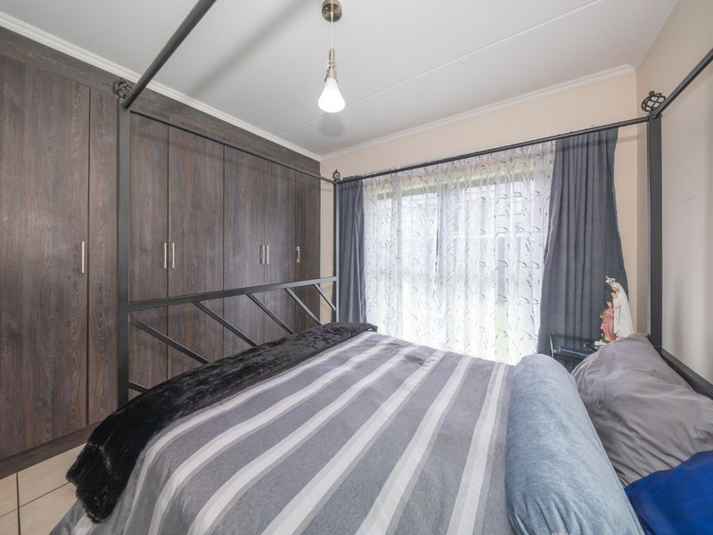A well-maintained bedroom featuring dark wood-finish built-in cupboards and a sliding glass door providing natural light.