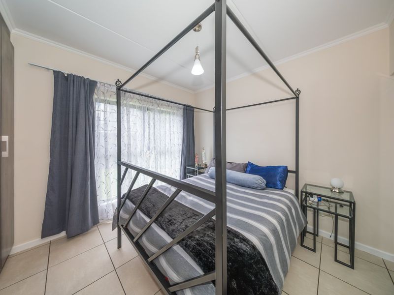 A well-maintained bedroom featuring tiled flooring, built-in cupboards, and a sliding glass door providing natural light.