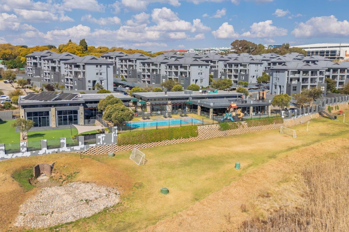 Aerial view of a residential townhouse complex featuring a communal swimming pool, clubhouse facilities, and landscaped outdoor areas.