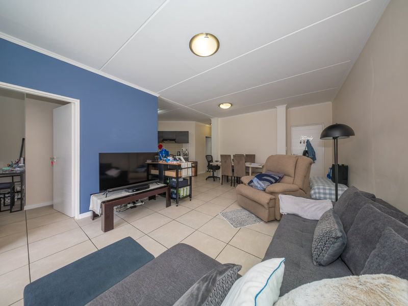 Open-plan living and dining area featuring tiled flooring and neutral wall tones, seamlessly connecting to the kitchen space.