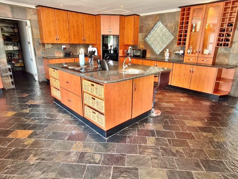 Spacious kitchen featuring a central island with granite countertops, extensive built-in cabinetry, and distinctive slate tile flooring and wall finishes.