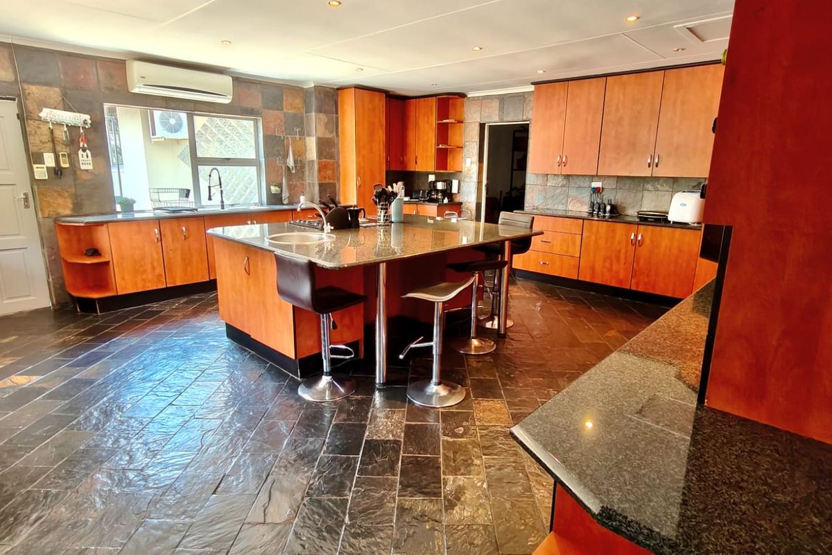 Spacious kitchen featuring wooden cabinetry, granite countertops, a central island, and slate tile flooring throughout.