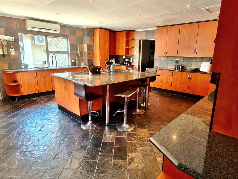 Spacious kitchen featuring wooden cabinetry, granite countertops, a central island, and slate tile flooring throughout.