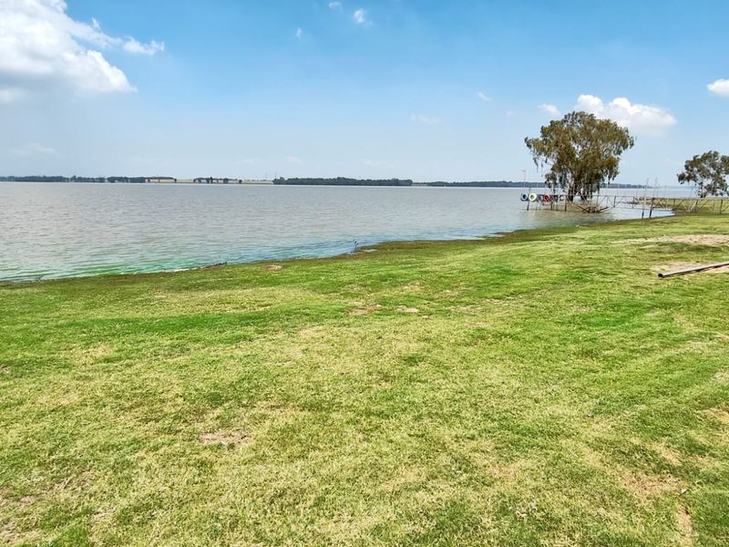 A scenic view of the expansive lakefront property featuring a well-maintained grass lawn leading down to the water's edge.