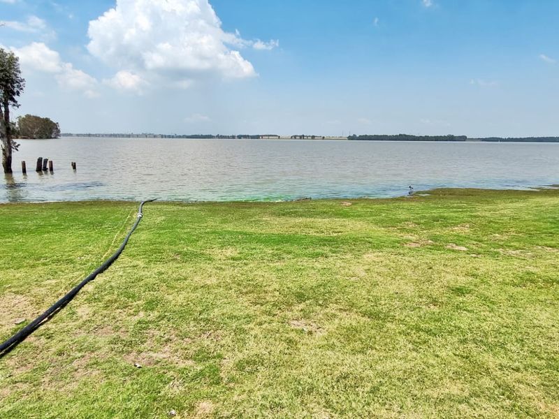 A scenic view of the expansive lakefront property featuring a well-maintained lawn and direct access to the water.