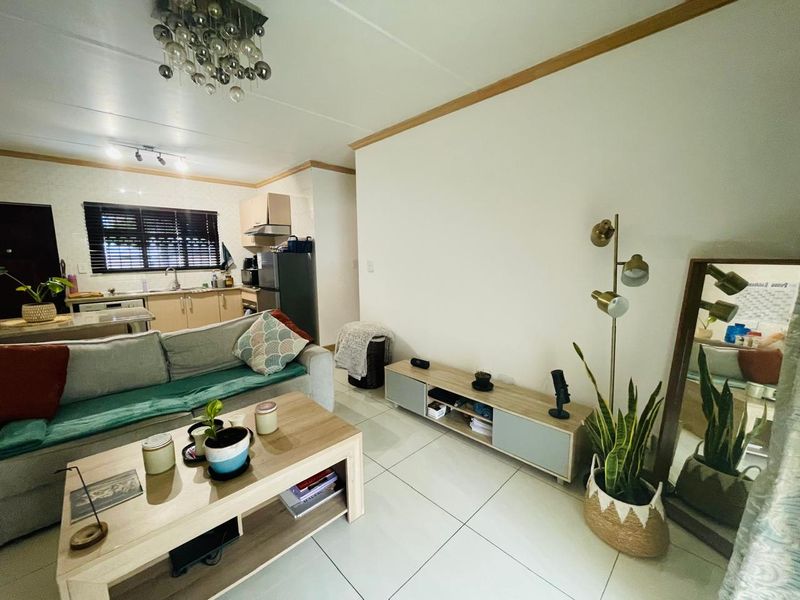 Open-plan living area featuring tiled floors and an integrated kitchen with cabinetry, providing a functional and connected space for daily living.