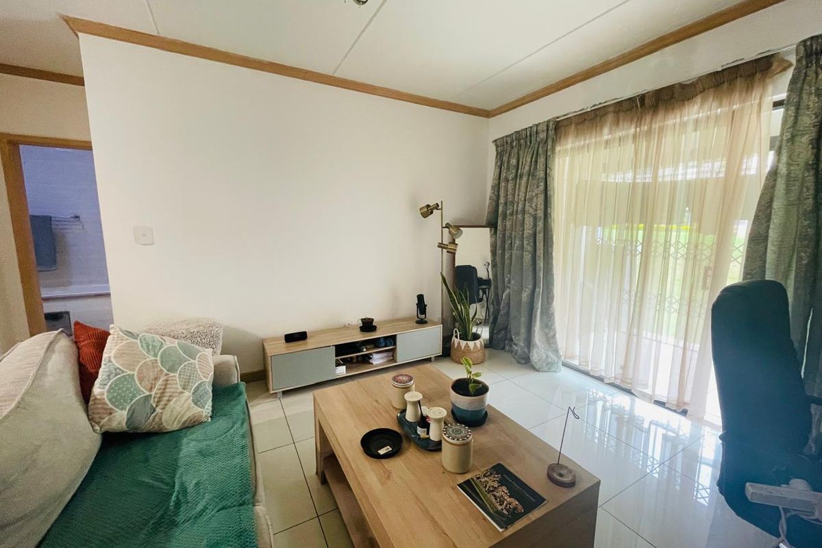 A bright living room featuring large format floor tiles and a sliding glass door providing access to the exterior.