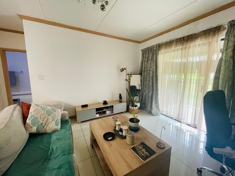 A bright living room featuring large format floor tiles and a sliding glass door providing access to the exterior.
