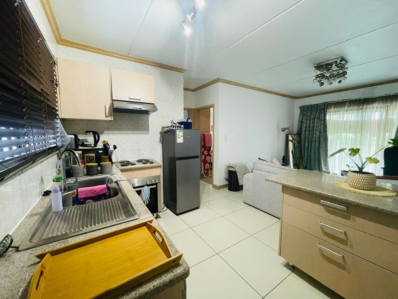 Open-plan kitchen and living area featuring tiled flooring, granite countertops, and built-in cabinetry with integrated stove and extractor fan.
