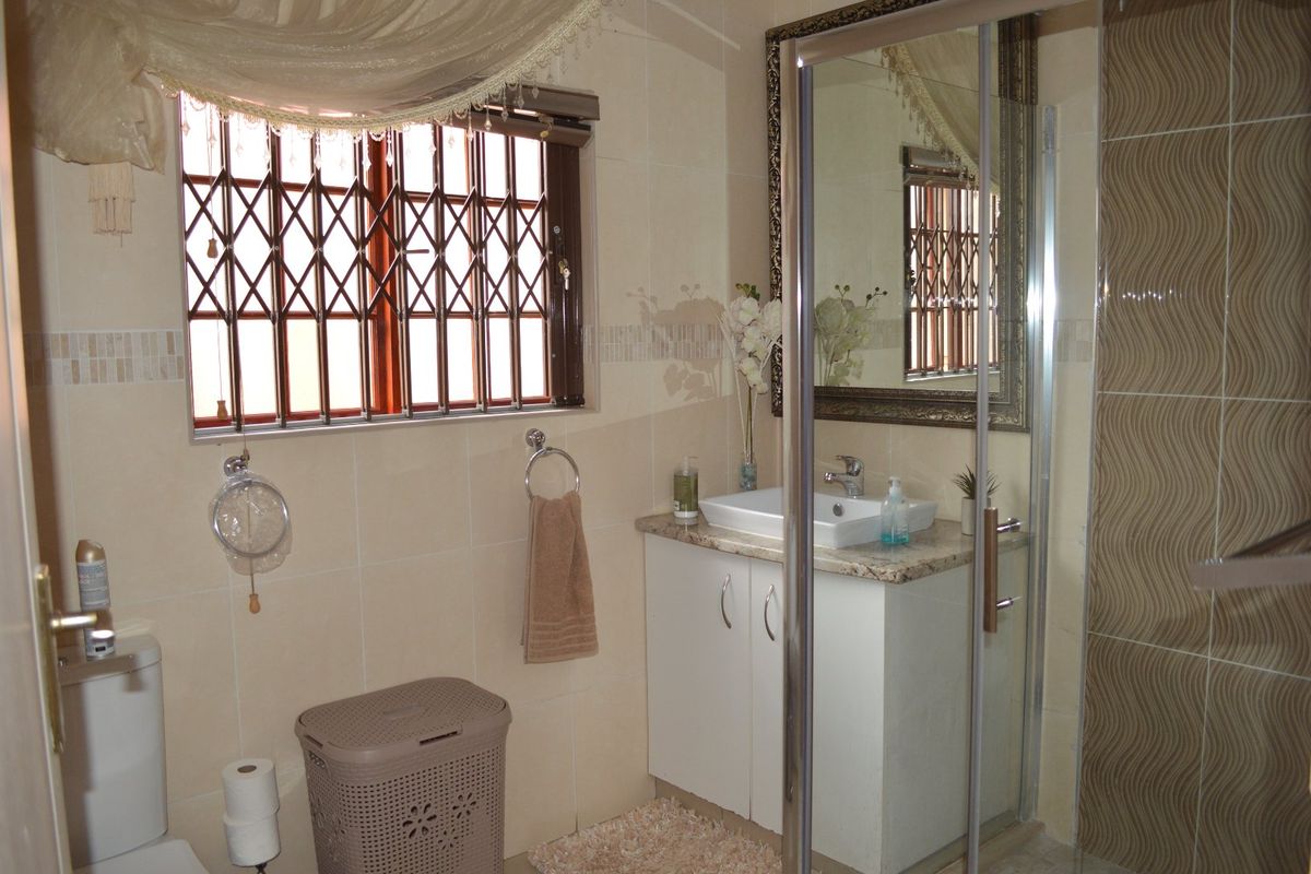 A functional bathroom featuring a vanity with a granite countertop, vessel sink, and a glass-enclosed shower with decorative wall tiling.