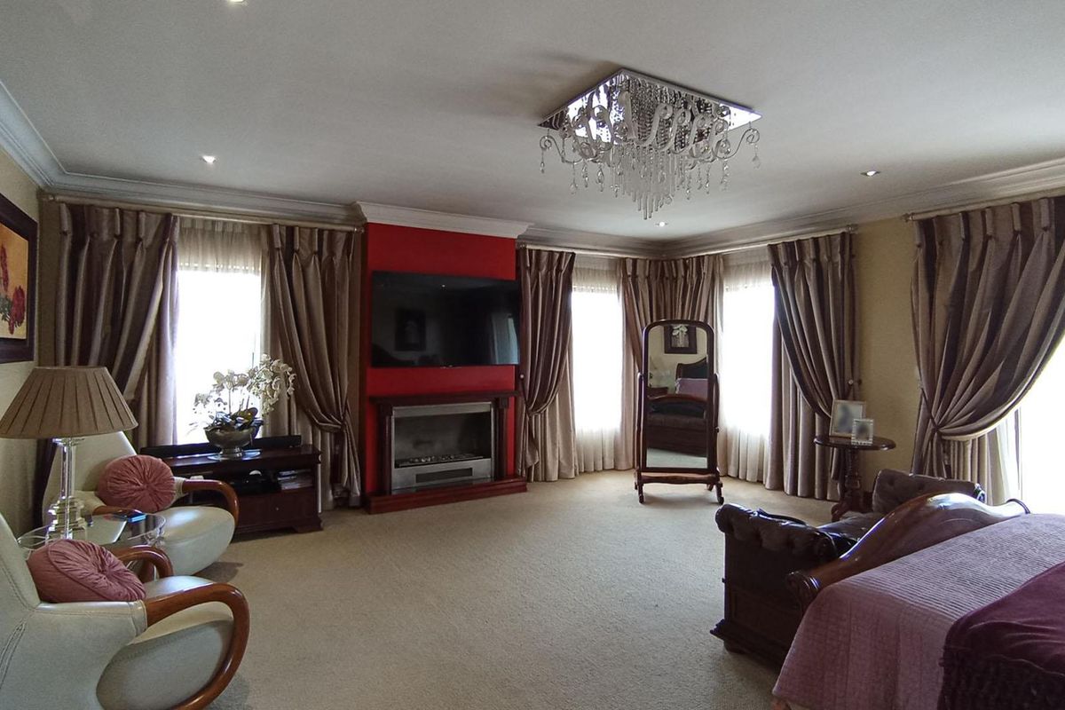 Spacious bedroom featuring a built-in fireplace, elegant crown molding, recessed lighting, and a decorative crystal chandelier.