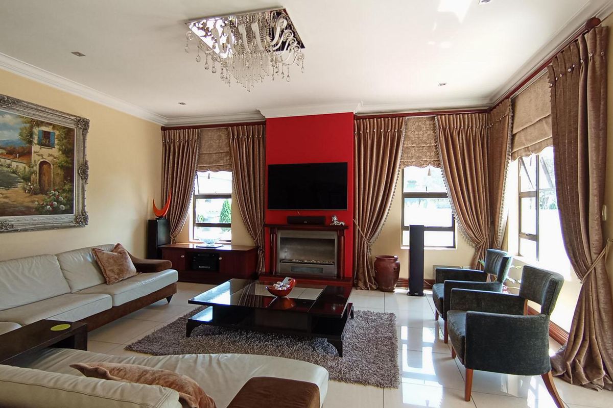 Spacious living room featuring a central built-in fireplace, tiled flooring, elegant crystal chandelier, and large windows with floor-to-ceiling drapery.