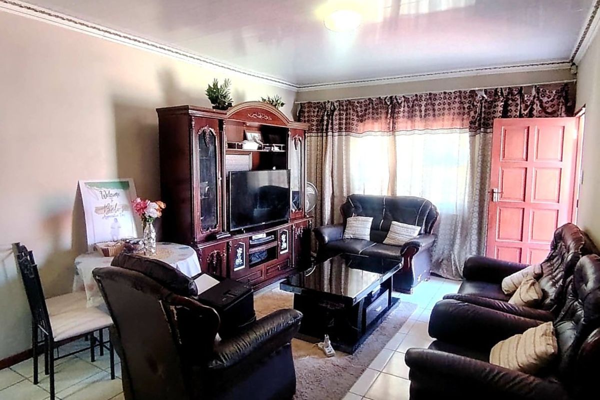 A living room featuring tiled flooring, coved ceiling details, and a panelled entrance door, providing a functional and lived-in space.