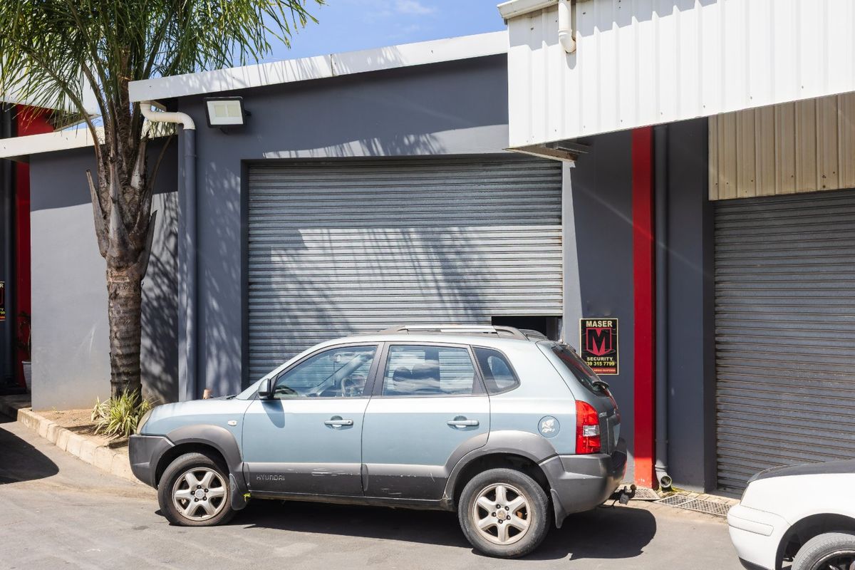 Industrial unit exterior featuring grey painted walls, metal cladding, and secure roller shutter door access.