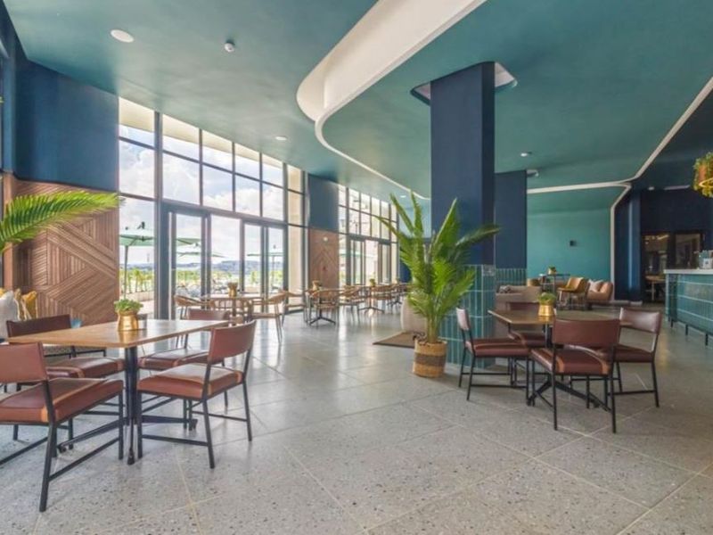 Spacious open-plan dining and lounge area featuring floor-to-ceiling windows, modern terrazzo flooring, and a stylish built-in bar with decorative tiling.