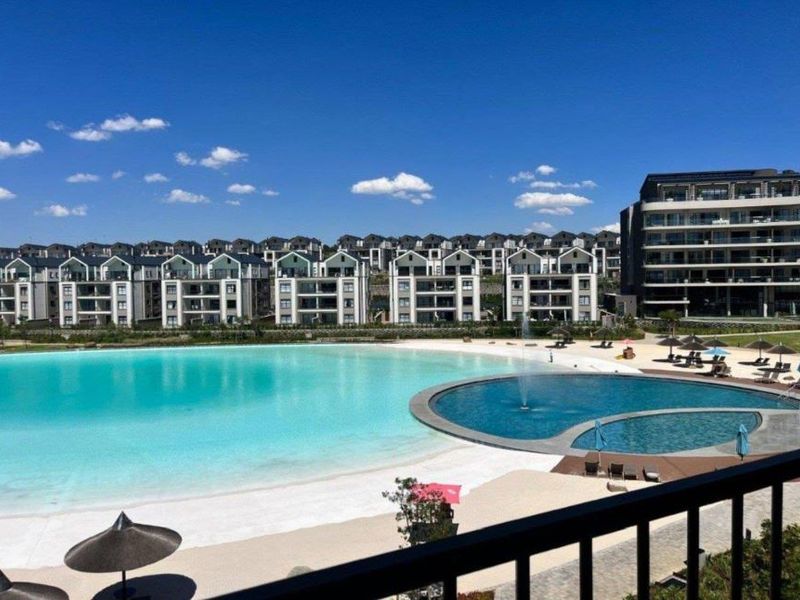 A scenic view overlooking a large man-made lagoon, swimming pool, and surrounding residential estate architecture.