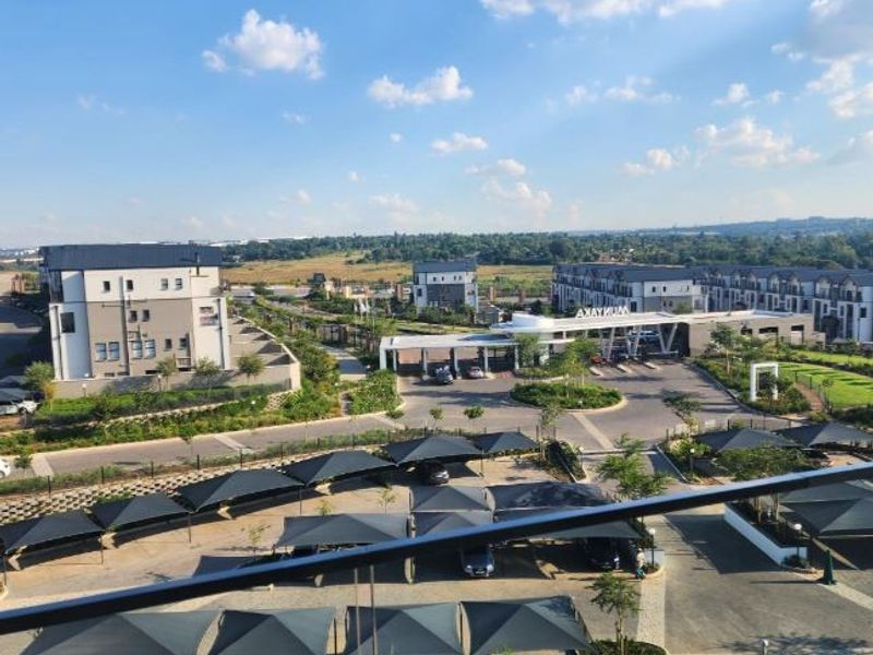 Elevated view overlooking the residential estate, featuring paved driveways, shade cloth carports, and the main security entrance gatehouse.