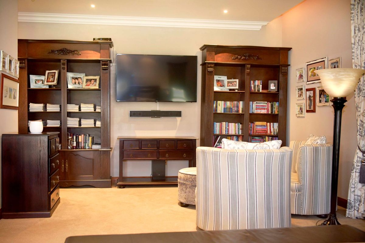 A comfortable living room featuring built-in dark wood cabinetry, recessed ceiling lighting, and neutral carpeting, creating a warm and functional space.