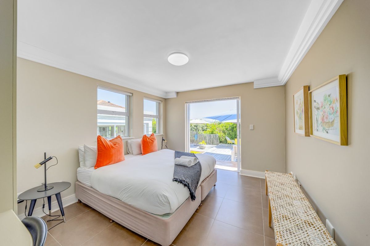 A bright bedroom featuring tiled flooring, crown molding, and a sliding glass door providing direct access to an outdoor patio area.