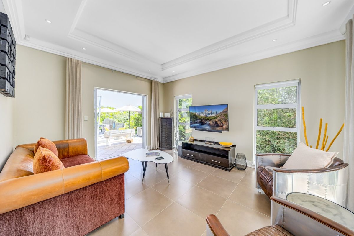 Bright and spacious living room featuring tiled floors, a recessed ceiling with downlights, and large sliding doors providing seamless access to the outdoor patio area.