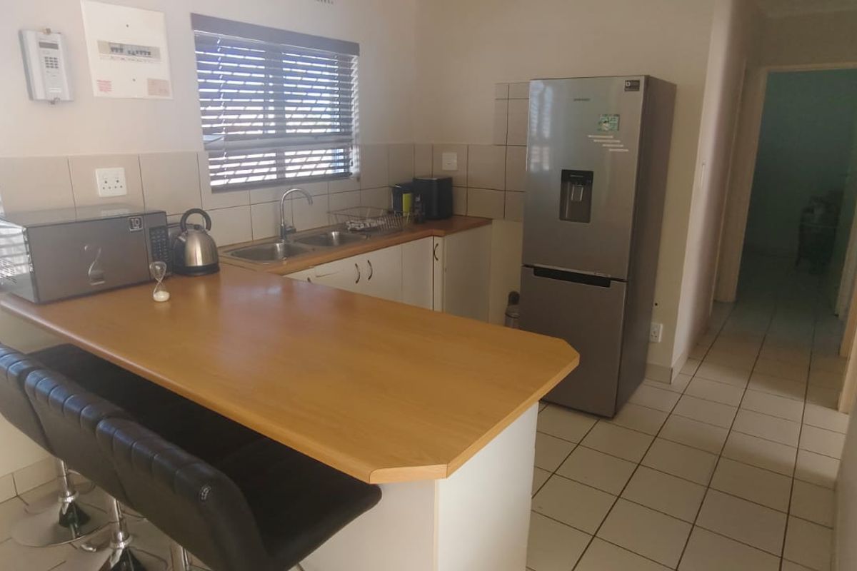 A functional kitchen featuring a breakfast bar, laminate countertops, tiled backsplash, and tiled flooring, providing a practical layout for daily meal preparation.