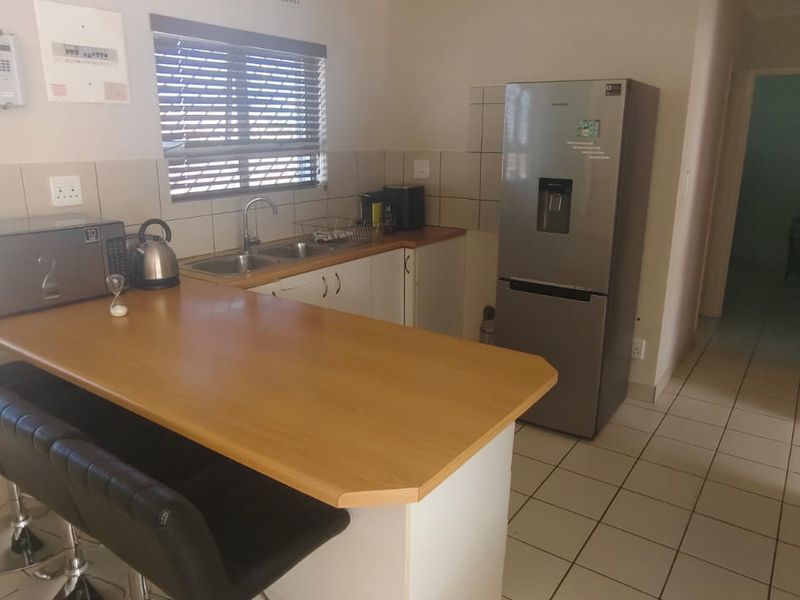 A functional kitchen featuring a breakfast bar, laminate countertops, tiled backsplash, and tiled flooring, providing a practical layout for daily meal preparation.