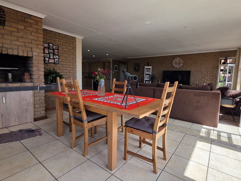 Spacious open-plan living and dining area featuring a built-in brick fireplace, tiled flooring, and large sliding glass doors providing natural light.