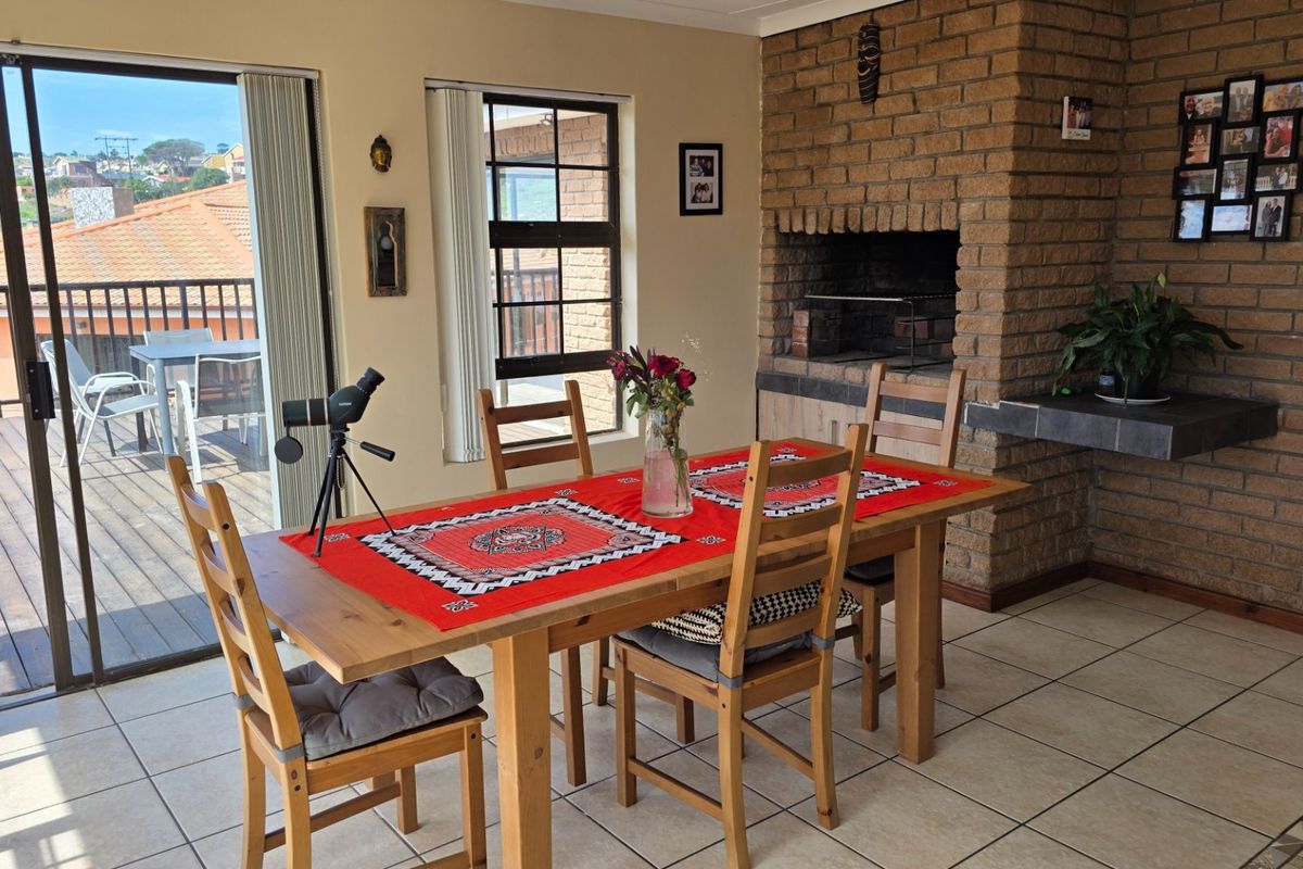 Spacious living area featuring a prominent built-in brick fireplace, tiled flooring, and direct access to an outdoor deck through sliding glass doors.