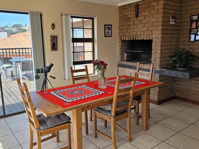 Spacious living area featuring a prominent built-in brick fireplace, tiled flooring, and direct access to an outdoor deck through sliding glass doors.