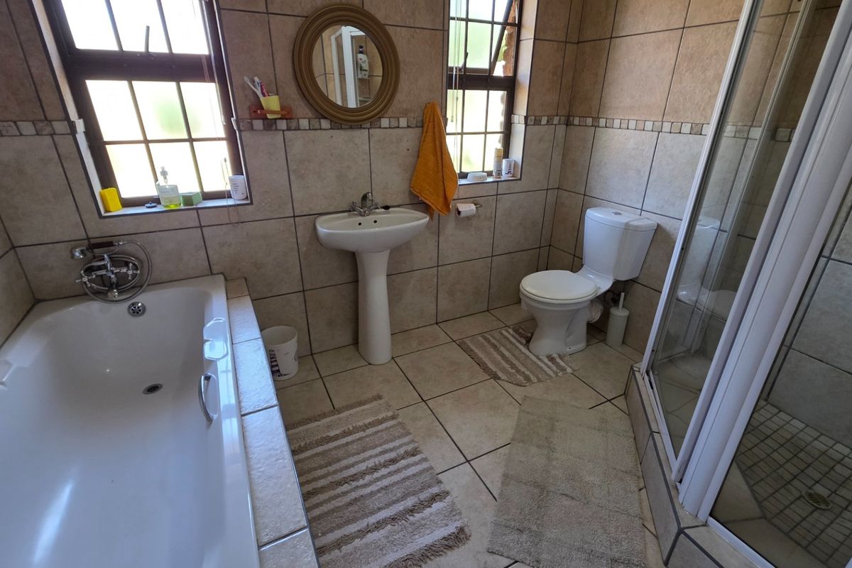A functional bathroom featuring a pedestal basin, bathtub, separate shower enclosure, and tiled finishes throughout.