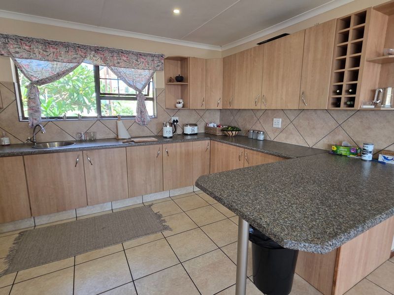 A functional kitchen featuring light wood-tone cabinetry, granite-look laminate countertops, a breakfast bar, and tiled flooring with a neutral backsplash.