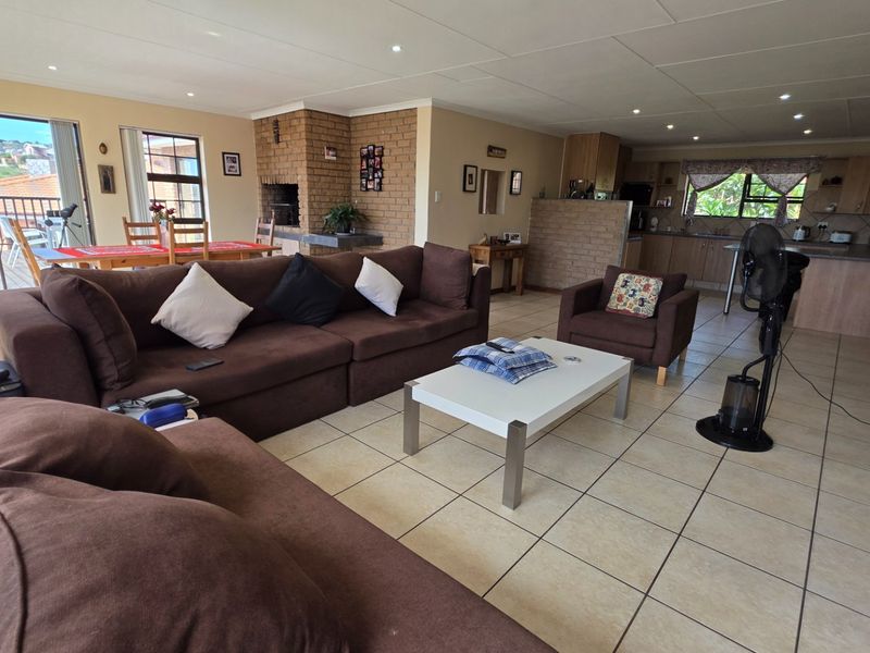 Spacious open-plan living area featuring a built-in brick fireplace, tiled flooring, and direct access to an outdoor balcony, seamlessly connected to the kitchen.