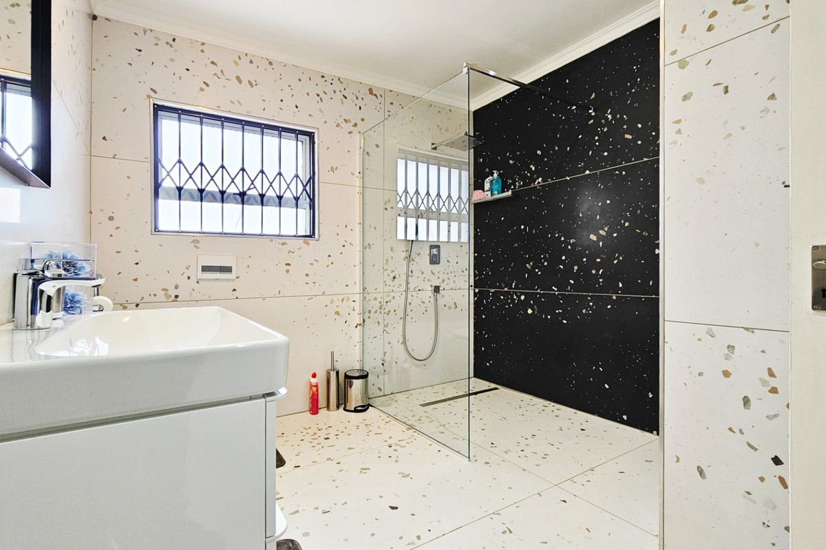 Modern bathroom featuring a spacious walk-in shower with glass screen, contemporary vanity basin, and stylish terrazzo-style tiling throughout.