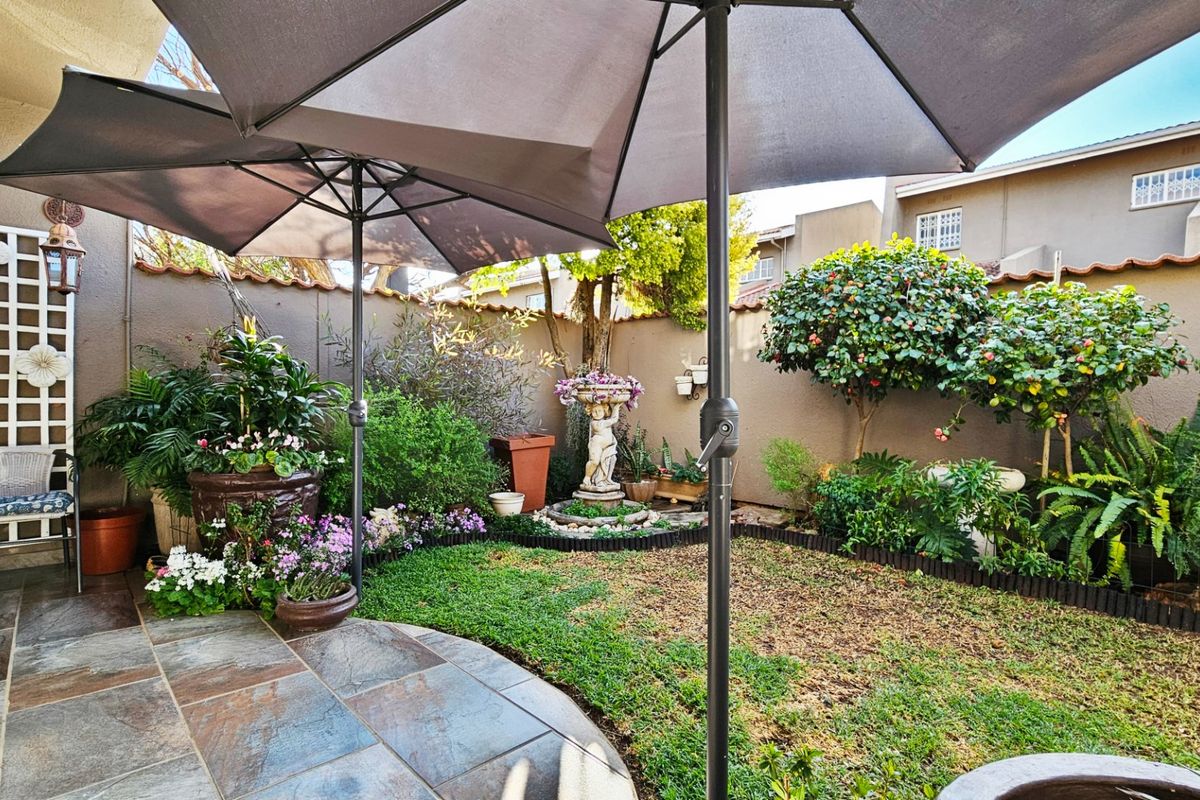 A private rear garden featuring a paved patio area, established landscaping, and secure boundary walls, ideal for outdoor relaxation.