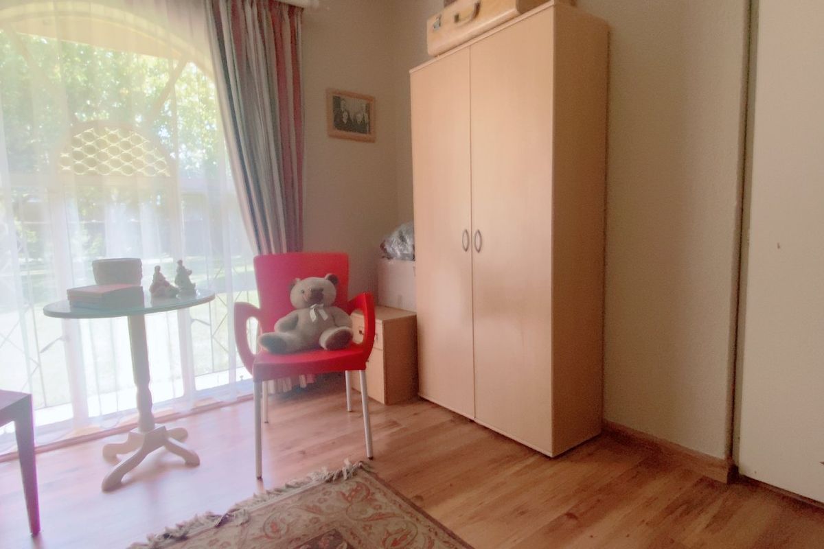 A bedroom featuring laminate flooring, a built-in wardrobe, and a large glass sliding door providing natural light and garden access.