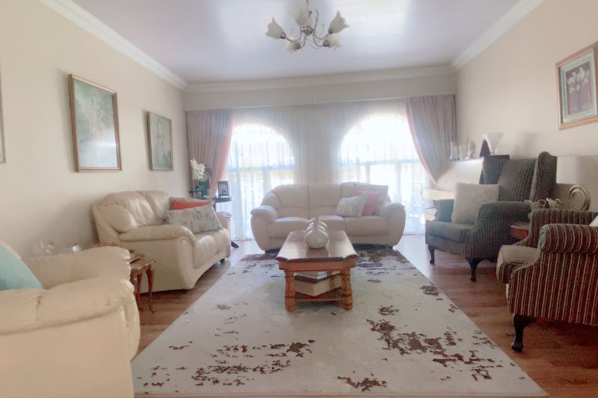 A spacious living room featuring arched windows, crown molding, and wood-look flooring, providing a comfortable and well-lit area for relaxation.