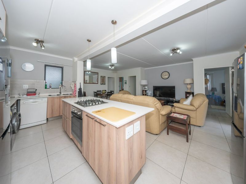 Spacious open-plan living area featuring a modern kitchen with a central island, gas hob, built-in oven, and tiled flooring throughout.