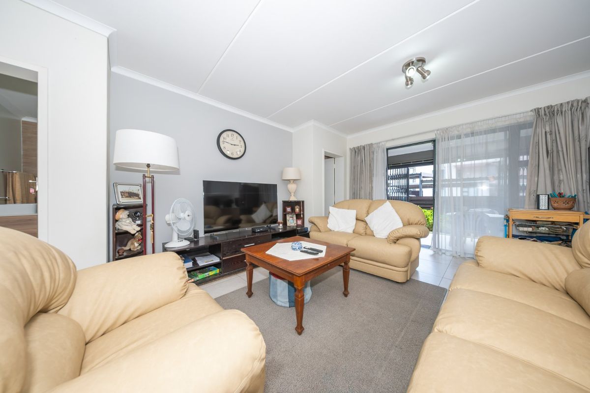 A comfortable living room featuring tiled flooring, neutral wall tones, and a sliding glass door providing access to the outdoor area.