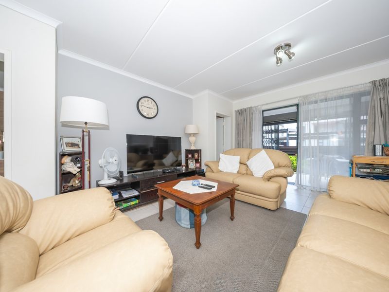 A comfortable living room featuring tiled flooring, neutral wall tones, and a sliding glass door providing access to the outdoor area.