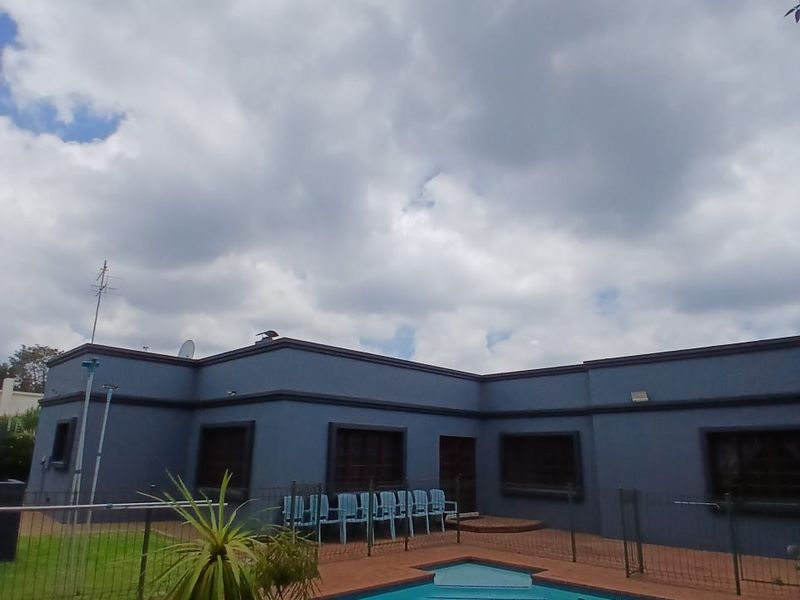 Rear exterior view featuring a swimming pool with a brick-paved surround, a small water feature, and perimeter fencing against the house facade.