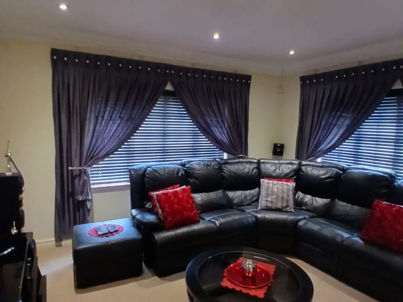 A comfortable living room featuring recessed downlighting, venetian blinds, and decorative coving, providing a neutral base for interior styling.