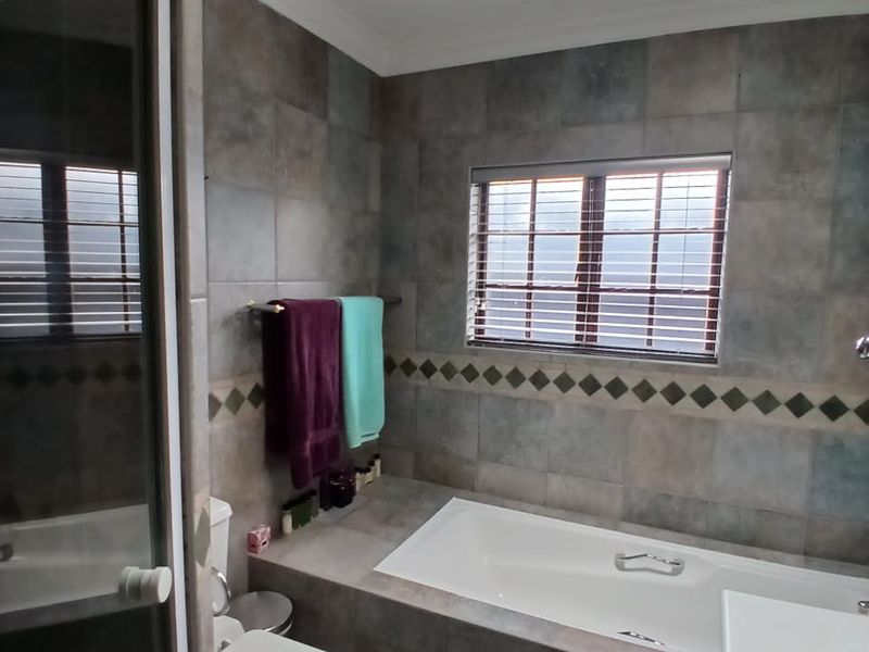 A functional bathroom featuring a built-in bathtub, separate shower enclosure, vanity basin, and a skylight for natural illumination.