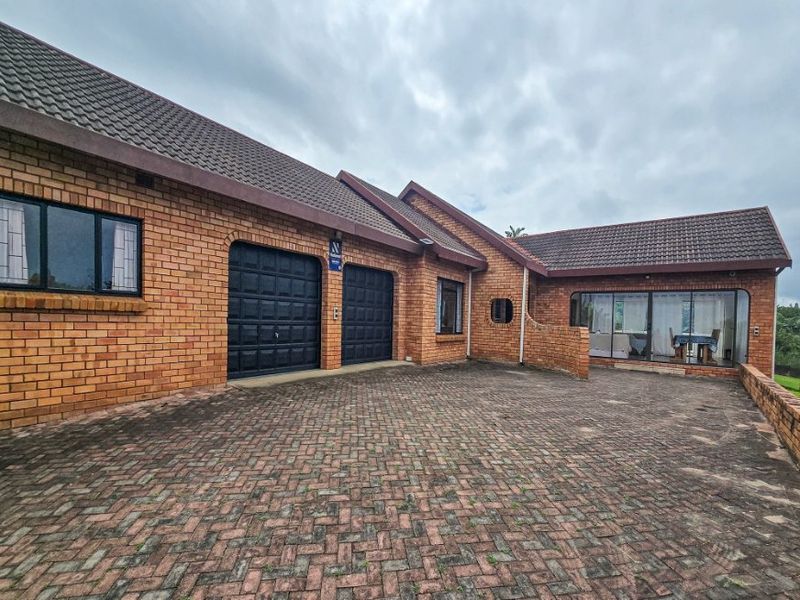 Front exterior view of a facebrick house featuring a double garage, paved driveway, and tiled roof.