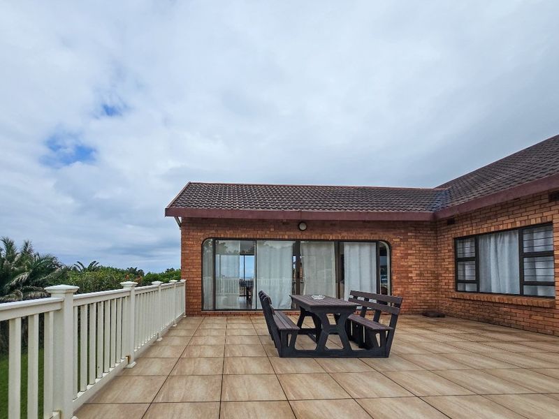 A spacious outdoor patio featuring tiled flooring, brick exterior walls, and sliding glass doors providing access to the interior living space.