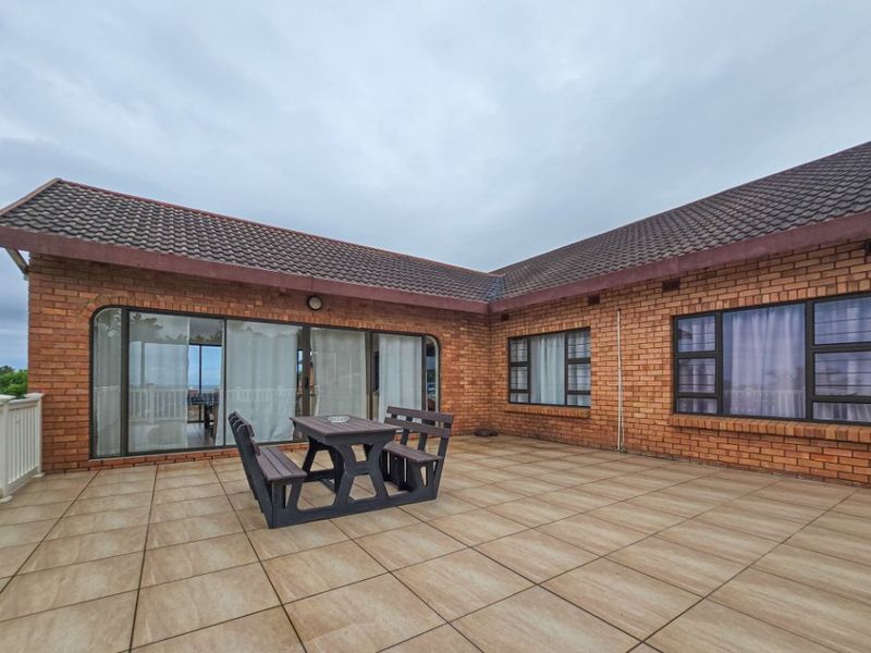 Spacious outdoor patio area featuring tiled flooring, brick exterior walls, and large sliding glass doors providing access to the interior.